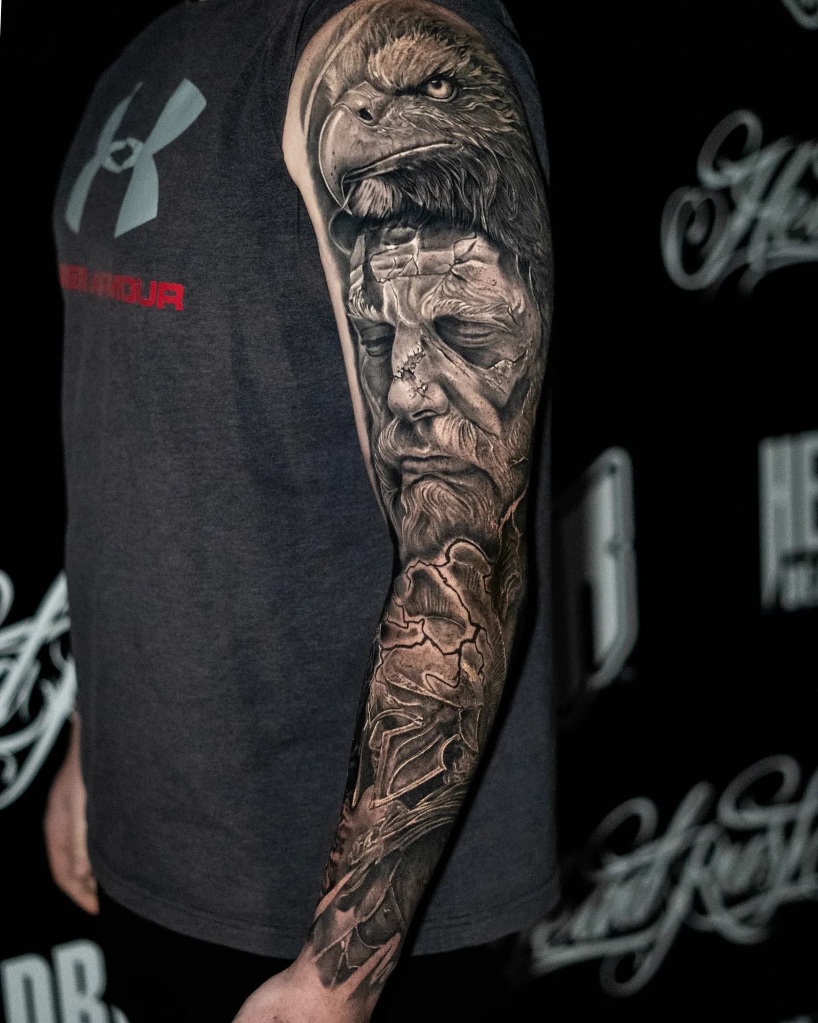 An arm sleeve: an eagle's head at the shoulder above a cracked stone face, bones down the forearm