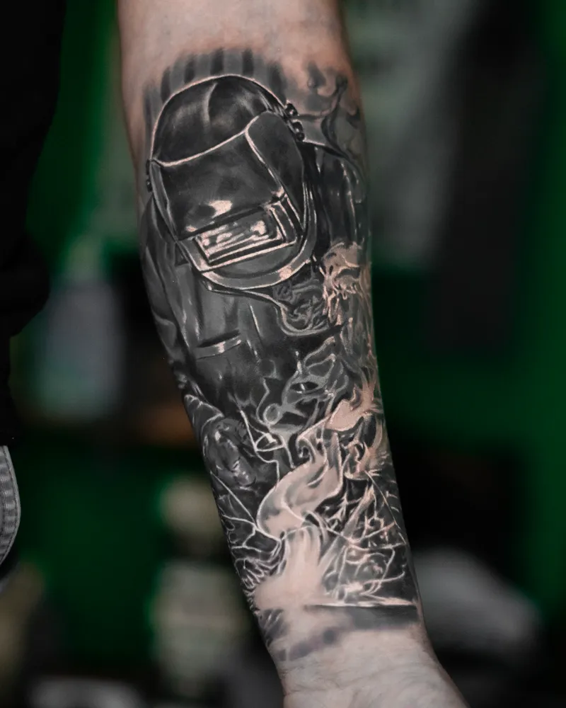 A forearm: a welder in a mask, sparks and smoke pouring down towards the wrist