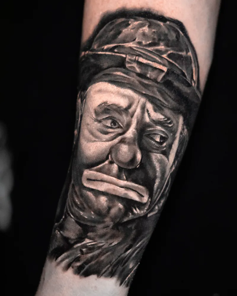 A forearm portrait of a sad-faced clown in a battered hat