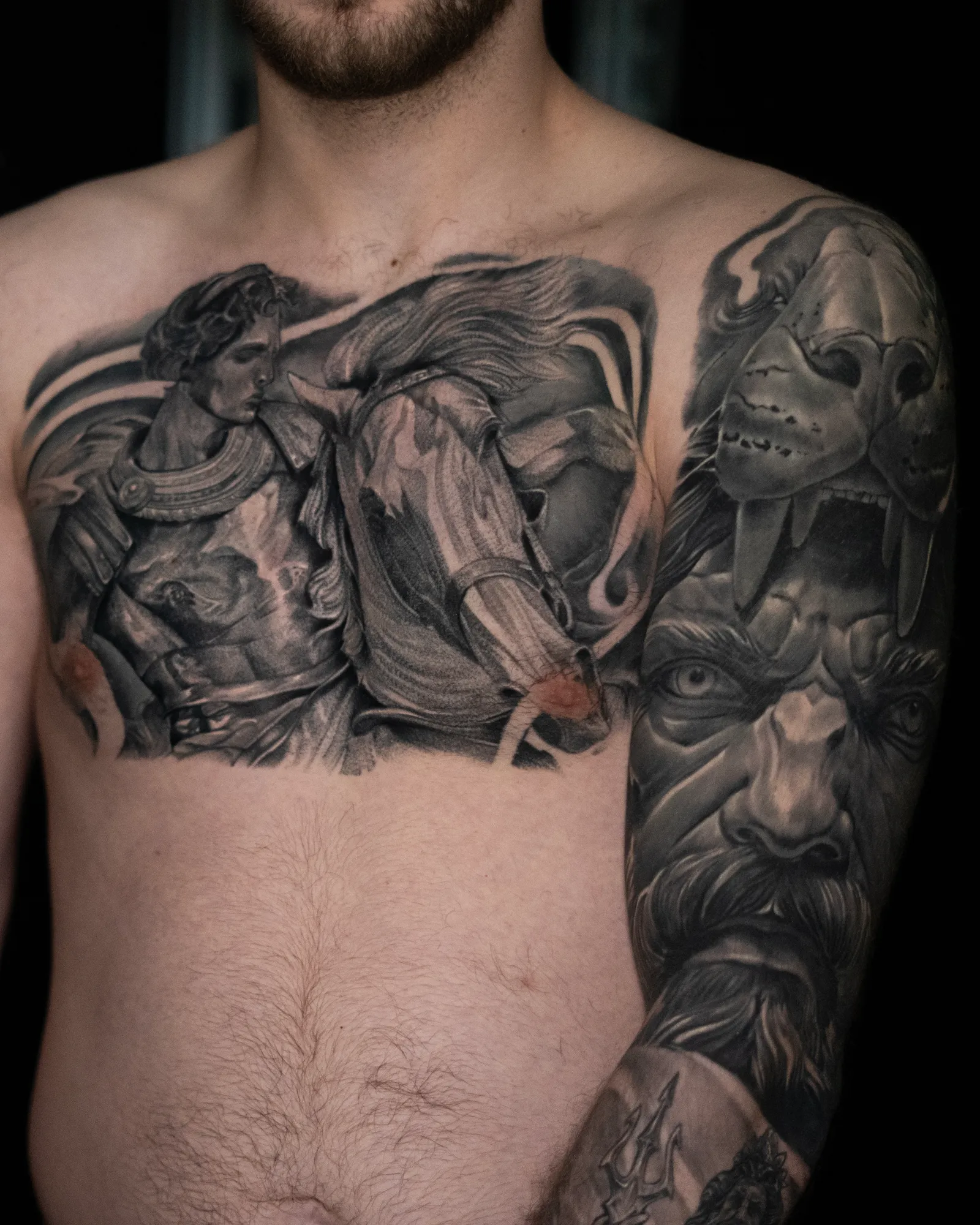 A healed chest and arm: an armoured warrior leading a horse across the chest, a fanged skull over a bearded face on the shoulder